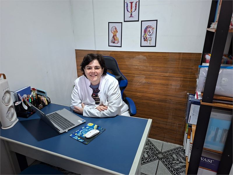 Ana Luiza sentada à mesa de atendimento no consultório